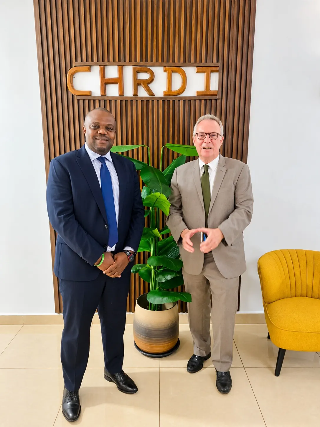 Two visitors beside the CHRDI office sign